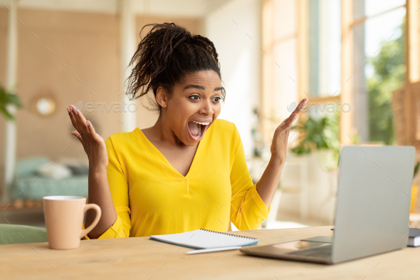Overjoyed african american lady looking at laptop and screaming WOW, being happy over huge sale in