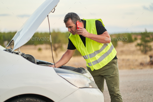 a man talking to the car insurance company to ask for travel assistance for a car breakdown