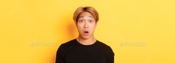 Close-up of surprised, speechless asian guy, drop jaw and raising eyebrows amazed, standing over