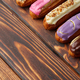 Assortment of sweet and colorful eclairs on wooden background - PhotoDune Item for Sale