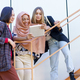 Smiling young diverse women using tablet on stairs - PhotoDune Item for Sale