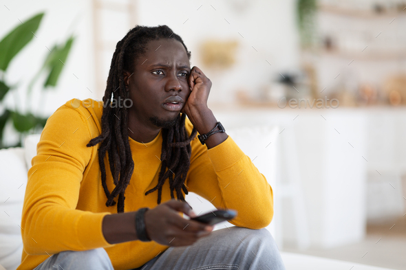 Boring Program. Portrait Of Bored Young Black Guy Watching TV At Home