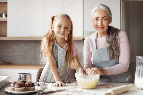 Granddaughter and grandma prepare cookies. Glad european little girl ...