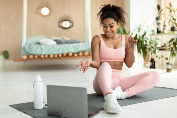 Online exercise session marathon. Happy black woman sitting on floor mat and talking with coach - Stock Photo - Images