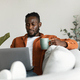 African american man working on laptop, holding cup and enjoying drinking morning coffee, sitting on - PhotoDune Item for Sale