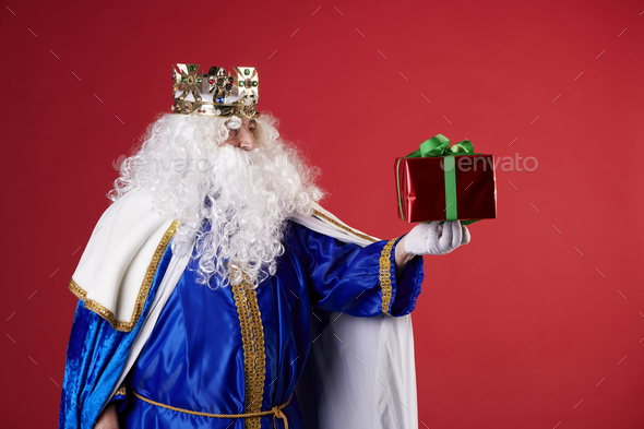 A magic king with a present on a red background