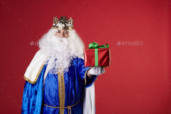 A magic king with a present on a red background