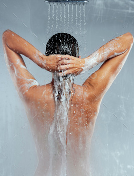 Shot of an unrecognizable woman washing her hair in the shower against a grey background