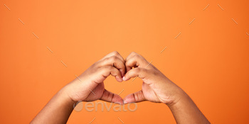Shot of an unrecognizable person showing a heart gesture against an orange background