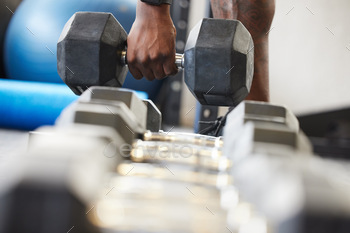 Time to go heavy. Closeup shot of an unrecognisable man exercising with a dumbbell in a gym.