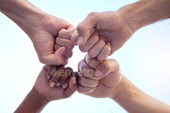 Shot of a group of people fist bumping one another in a circle