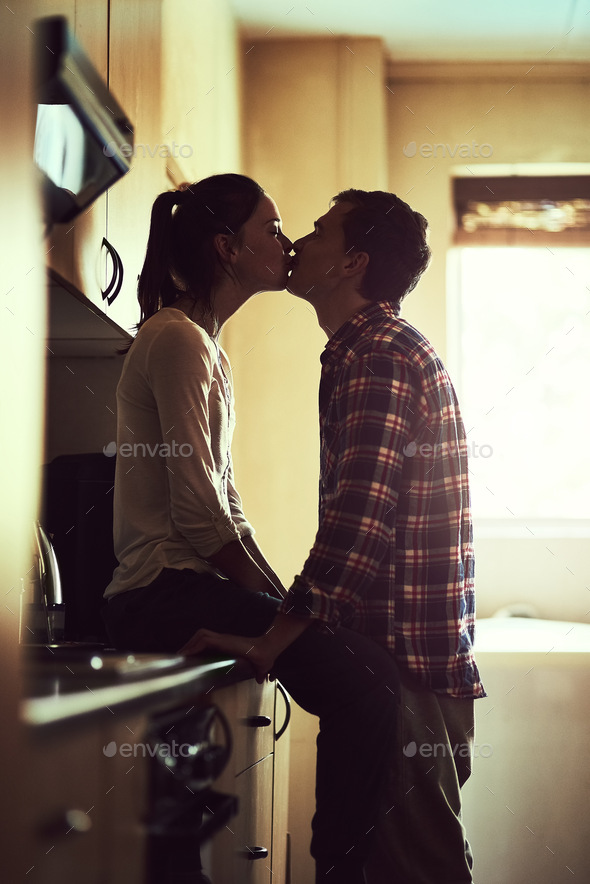 Lip locked lovebirds. Shot of an affectionate young couple sharing a romantic kiss in the kitchen.