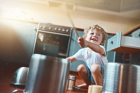 Portrait of an adorable little boy playing with pots in the kitchen ...