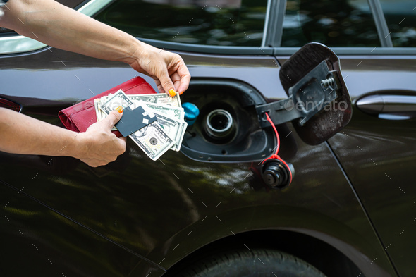 female with cash and credit card in front of open gas tank, fuel price rise concept, hands close-up
