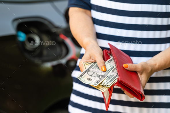 a woman counts money standing at an open fuel tank, the concept of rising fuel prices, closeup