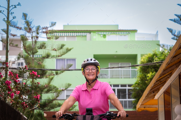 Senior active woman cycling in the city on her electric bicycle, sustainable mobility