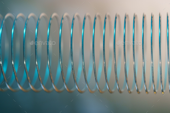 Closeup of coiled metal spring with sufficiently high strength and elastic properties in neon light