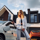 Young woman in white clothes is with her electric car at daytime - PhotoDune Item for Sale