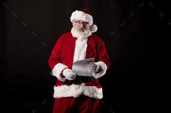 Santa Claus reading a letter on black background