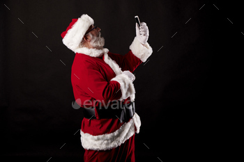 Santa Claus taking a selfie with a mobile phone on a black background
