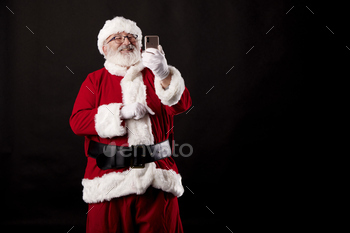 Santa Claus taking a selfie with a mobile phone on a black background