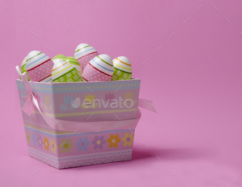 Colored Easter eggs in paper basket pastel colors on pink background. Easter theme.