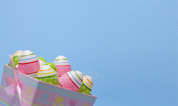 Colored Easter eggs in paper basket pastel colors on blue background. Easter theme.