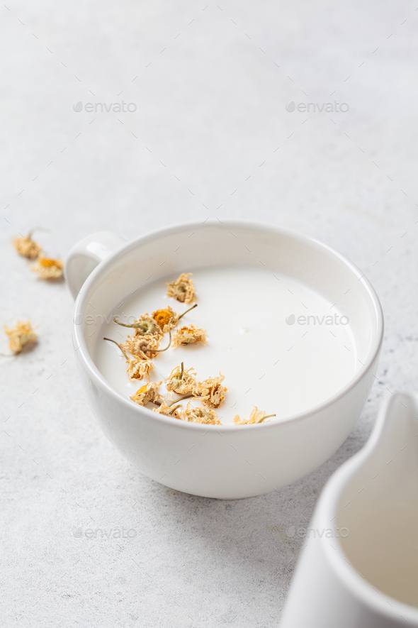 Chamomile moon milk in white cup. Ayurveda drink, chamomile latte tea. Stock Photo by vaaseenaa