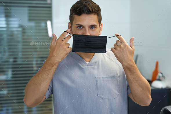 Handsome doctor demonstrating a way to put mask on