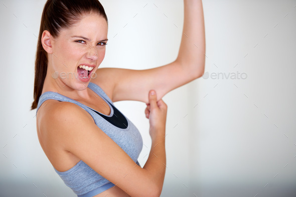 Flabby arms. Portrait of an attractive young woman grabbing her arm fat and looking upset.