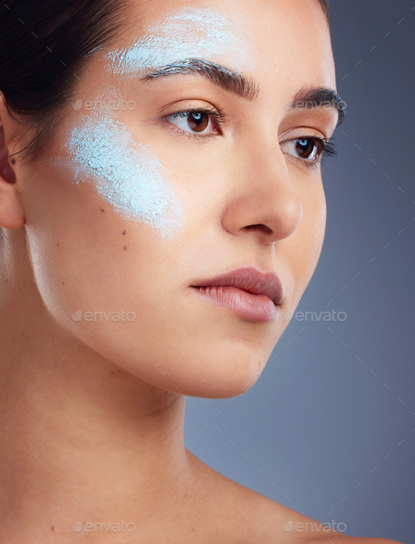 Studio portrait of a beautiful young woman covered in face paint posing  against a blue background Stock Photo by YuriArcursPeopleimages