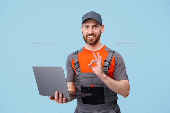 Handsome smiling delivery man in uniform with laptop looking at camera ...