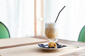 Latte macchiato in tall glass close up. Coffee on a table in cafe.Cappuccino coffee in elegant glass