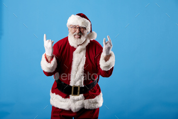 Santa Claus making a rocker gesture on a blue background