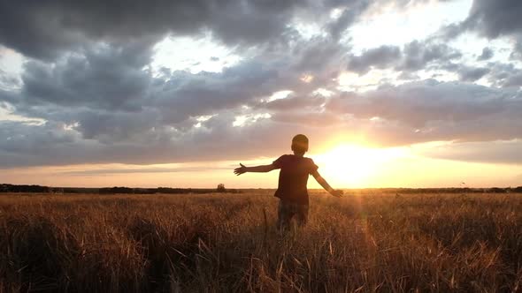 boy in a dark t-shirt and plaid shorts running on a wheat field. alt