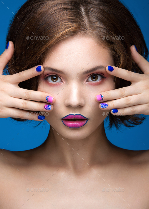 Beautiful model girl with bright makeup and colored nail polish. Beauty face. Short colorful nails