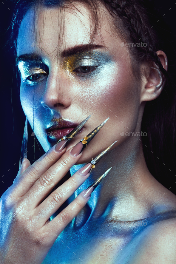 Beautiful girl with creative golden and silver glitter make-up, long nails art. beauty face.