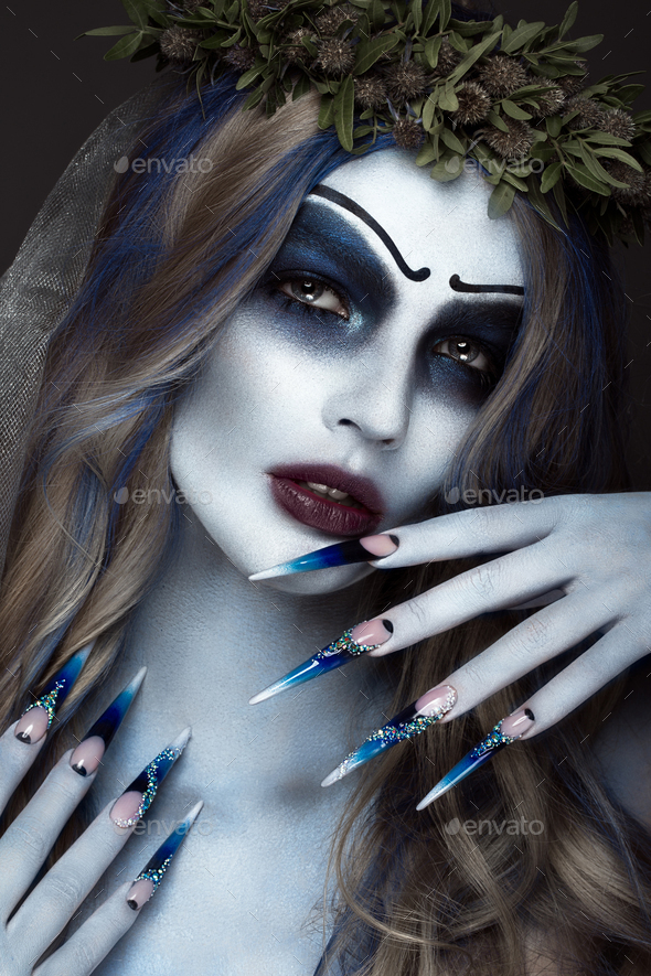 Portrait of a horrible scary Corpse Bride in wreath with dead flowers, halloween long manicure