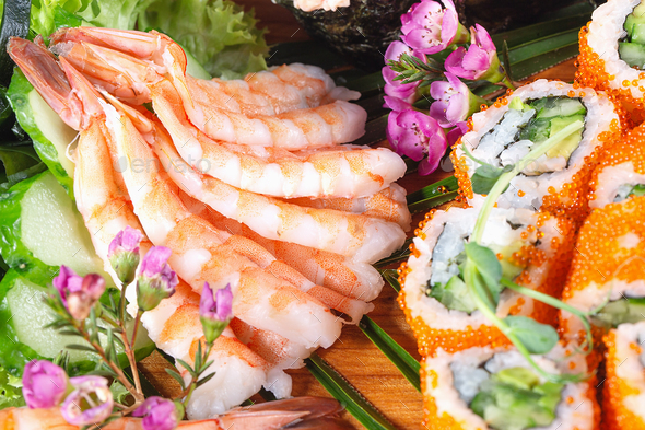 King prawns on plate with rolls and sushi decorated with sakura flowers - Stock Photo - Images