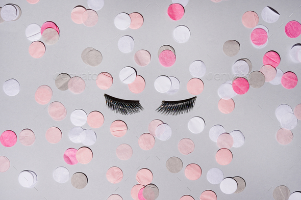 Black false lashes strips on grey background with colored confetti
