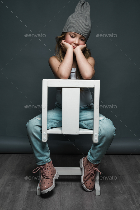 Little girl model professionally posing in the studio in jeans and a white T-shirt. Model tests