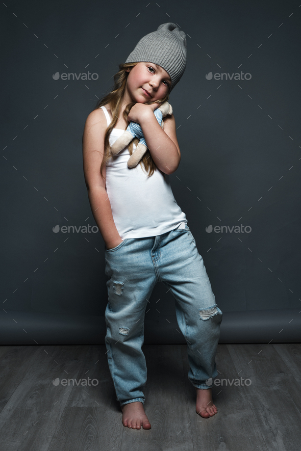 Little girl model professionally posing in the studio in jeans and a white T-shirt. Model tests