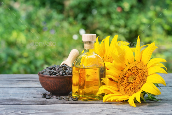 Sunflower seeds and flowers with bottle of oil on wooden table - Stock Photo - Images