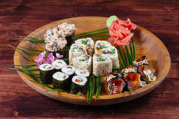 Sushi and rolls on wooden plate with spices and green leaves - Stock Photo - Images