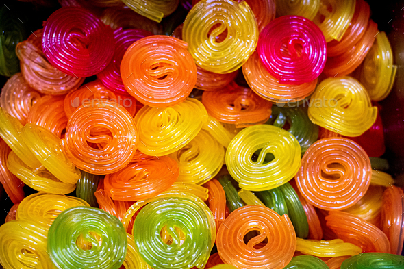 Multicolored jelly swirl candies background - yellow, red, orange transparent rolls.