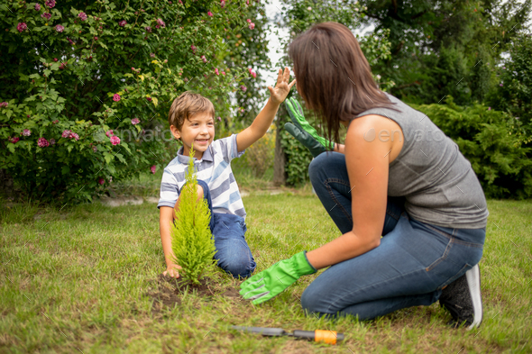 Mom and son planting plant together in garden