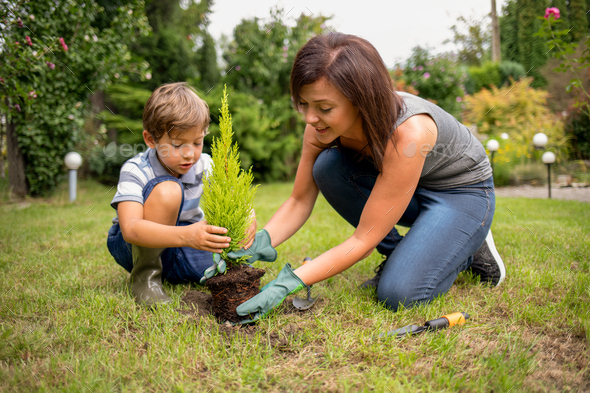 Mom and son planting plant together in garden