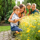 Happy family in garden looking at plants on sunny day - PhotoDune Item for Sale