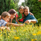 Happy family in garden looking at plants on sunny day - PhotoDune Item for Sale
