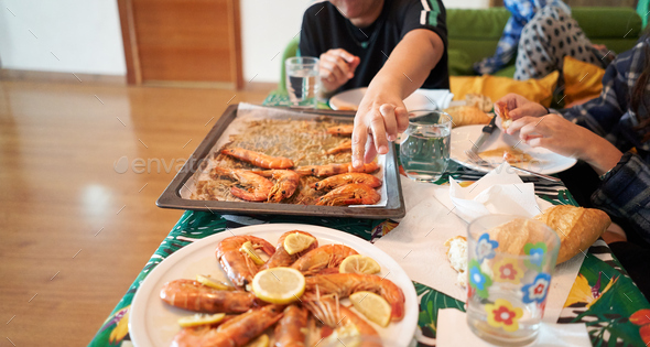 Family eats red prawns with lemon. Ready to eat.